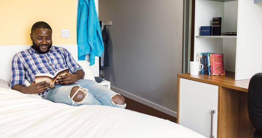 Student lying on his bed and reading a book